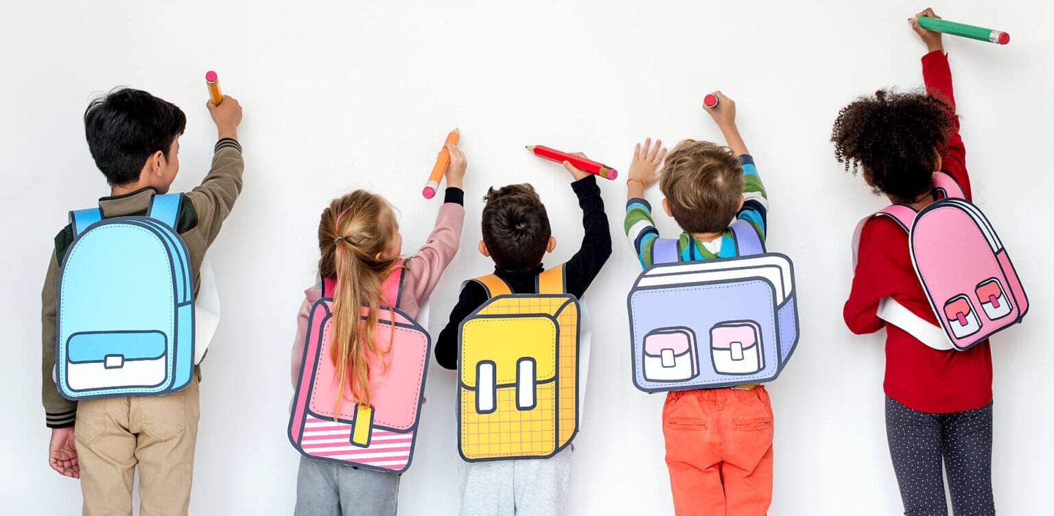 Schulkinder malen mit großen Stiften auf einer Wand.
