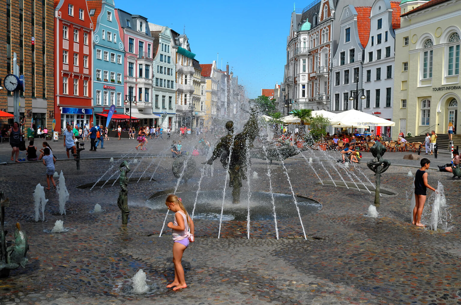 Sommer in der Rostocker Innenstadt. Kinder spielen in einem Springbrunnen.
